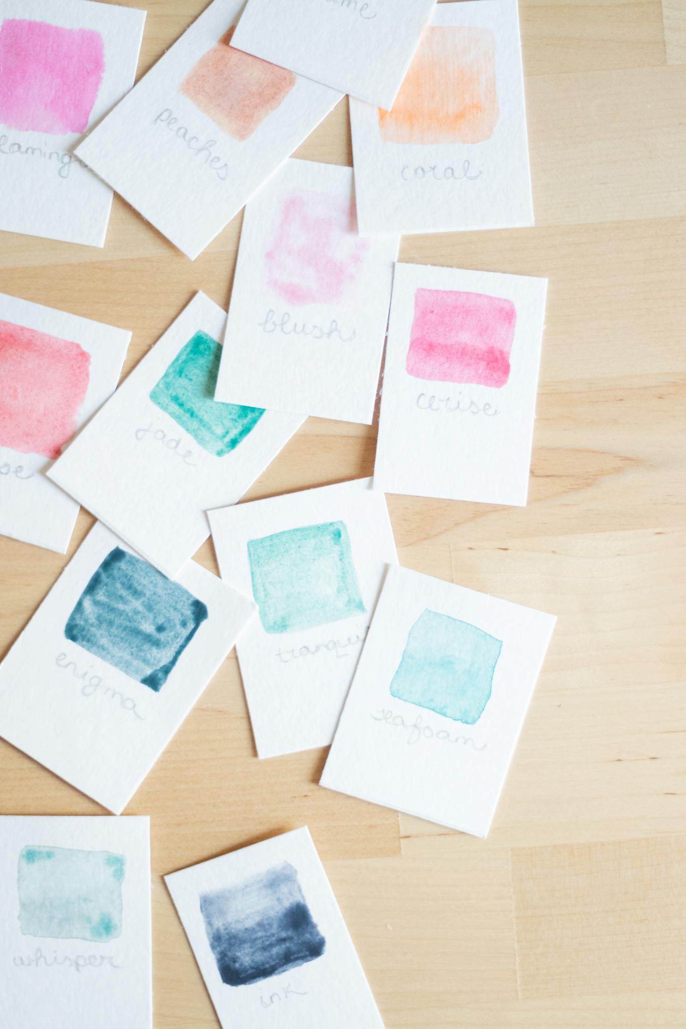 Bright watercolor paint swatches on wooden table, showcasing diverse color hues.