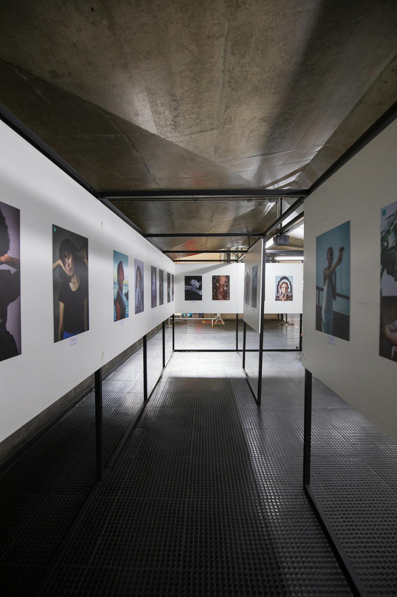 Contemporary art gallery showcasing diverse portraits in an industrial setting.