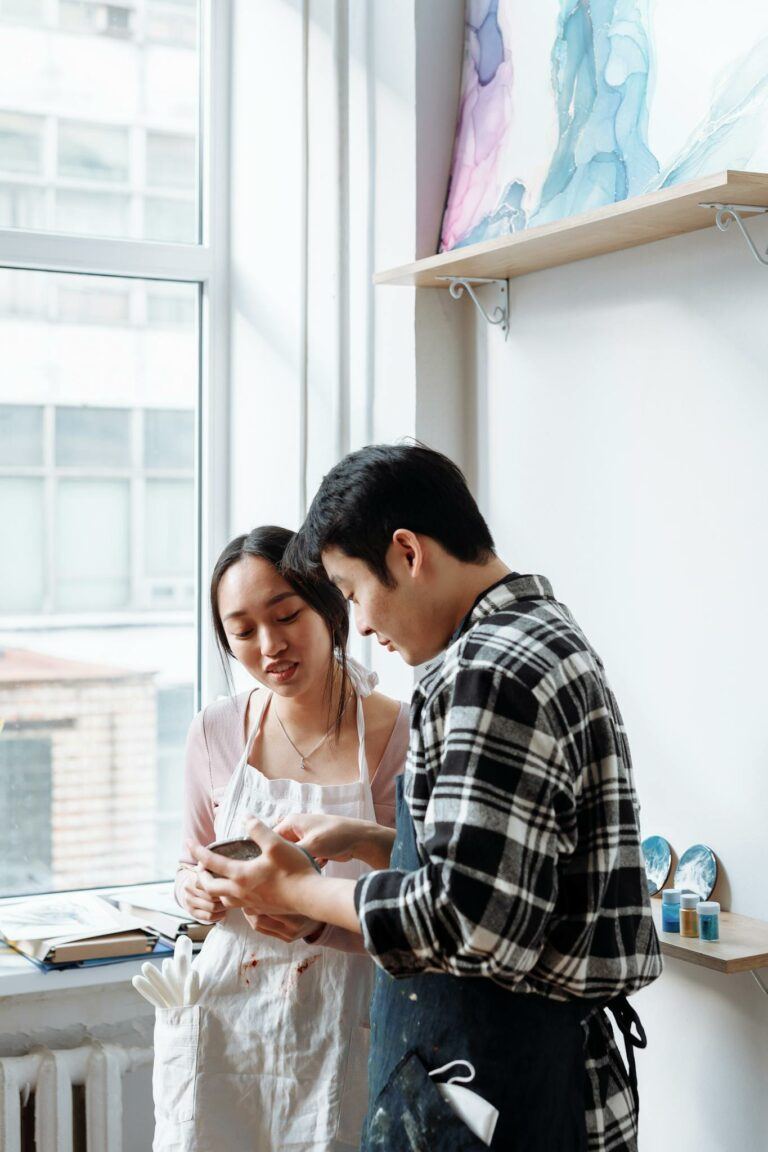 Two artists engaged in conversation in a bright, modern art studio.