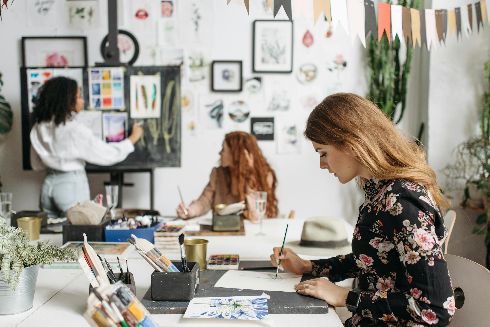 Women engaged in an art workshop with painting tools, creating art together in a studio setting.